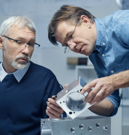 two engineers collaborating over a cnc machined critical component for the aerospace industry